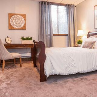 A cozy bedroom with elegant decor, featuring a comfortable bed and a wooden desk by the window.