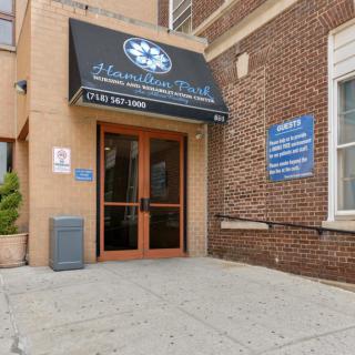 Entrance to a building with a black awning and brick exterior.