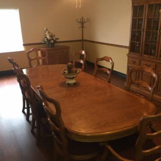 A neatly arranged dining room with a large wooden table and matching chairs.