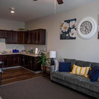 A cozy living room with a connected kitchen, featuring modern furniture and decor.