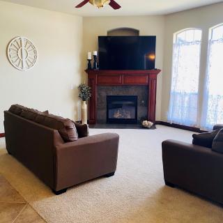 A cozy living room featuring a fireplace, large TV, and comfortable seating.