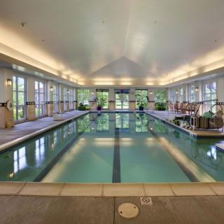 A spacious indoor swimming pool with natural light filtering through large windows.
