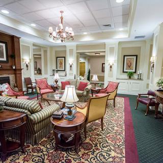 A traditional living room featuring elegant furniture, a chandelier, and a patterned carpet.