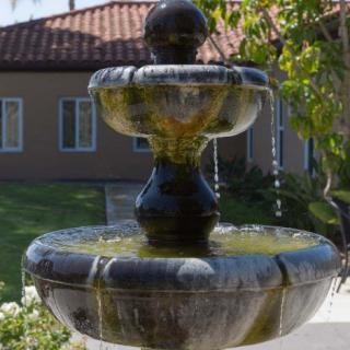 A decorative outdoor fountain with cascading water in a garden setting.