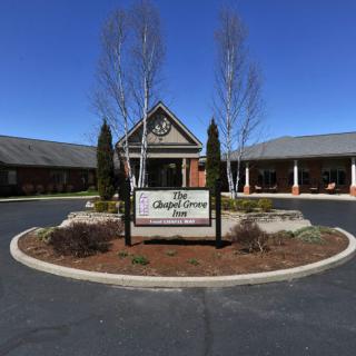 A building entrance with a central sign and landscaped surroundings under a clear blue sky.