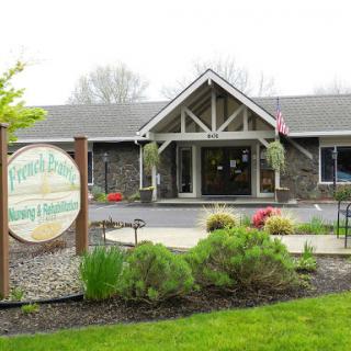 A welcoming entrance to a rustic building surrounded by lush landscaping and colorful flowers.