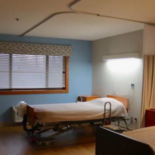 A clean and empty hospital room with a single bed and medical equipment.