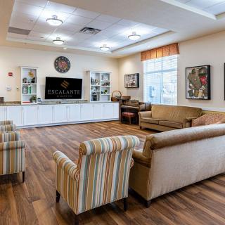 A cozy living room interior with sofas, stylish chairs, a large television, and warm wood flooring.