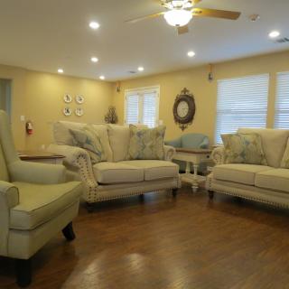 A cozy living room with comfortable sofas, armchairs, and warm lighting.