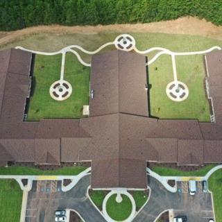Aerial view of a symmetrical building with landscaped gardens and pathways.