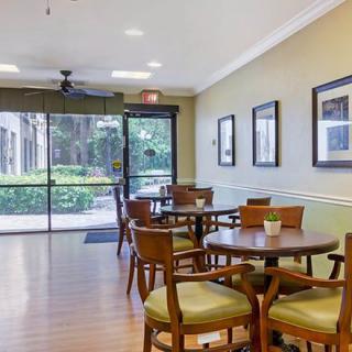 A cozy dining area with wooden tables and chairs, adorned with wall art and ample lighting.
