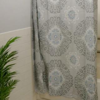 A bathroom with a patterned shower curtain and a potted plant.
