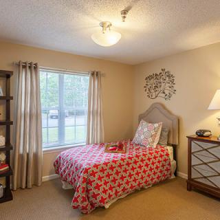 A cozy bedroom with a single bed, window, and decorative elements.