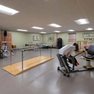 A well-equipped physical therapy room featuring exercise bars, rehabilitation equipment, and ample space for patient exercises.