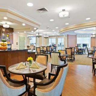 A modern dining area with neatly arranged tables and chairs, featuring elegant lighting and decor.