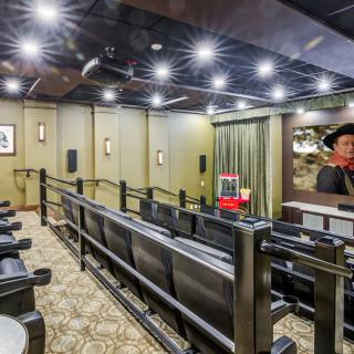 A spacious home theater with tiered seating, featuring a large screen, projector, and a classic popcorn machine.