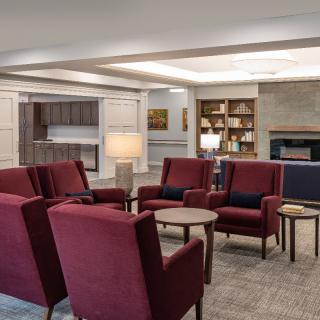 A cozy lounge area featuring red armchairs and a bookshelf.
