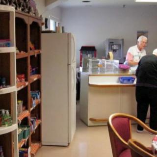 A kitchen area with shelves and people preparing food.