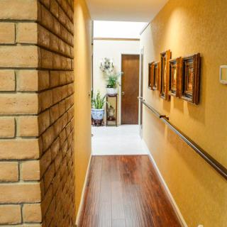 A cozy hallway with wooden flooring, adorned with paintings on the wall and a brick accent.