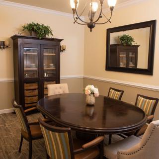 Elegant dining room with a round table, chairs, chandelier, and decorative mirror.