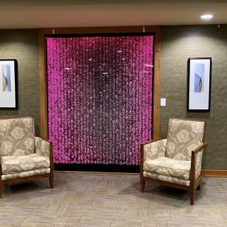A modern lobby area with two patterned chairs and a colorful digital artwork on the wall.