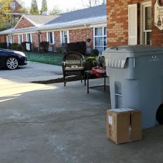 A tidy garage area with a parked vehicle, a package on the ground, and outdoor furniture.