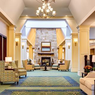 A spacious lobby featuring comfortable seating, a central fireplace, and elegant lighting.