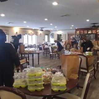A community dining hall set up with food packages as people prepare for an event.