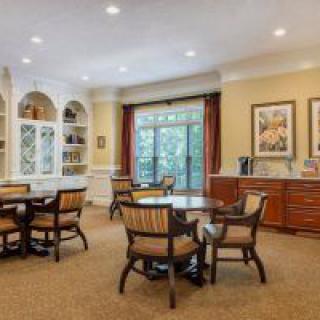 A cozy living room with dining tables, chairs, and built-in bookshelves.