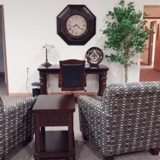 A cozy office setup featuring a desk, decorative clock, and patterned chairs.