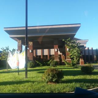 A modern building surrounded by lush greenery under a clear blue sky.