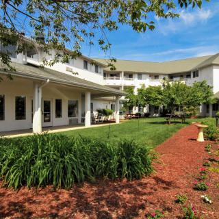A well-maintained residential building with a landscaped garden and trees.