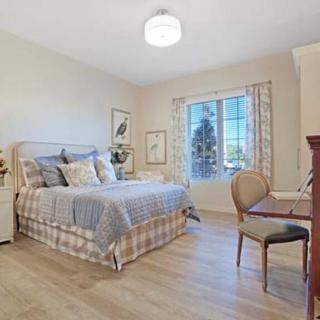 A cozy and well-decorated bedroom with a large bed, a desk with a chair, and natural light coming through the window.
