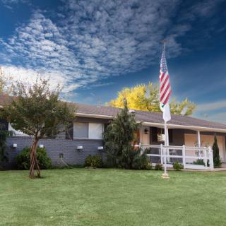 A suburban house with a well-maintained lawn and an American flag flying in the front yard.