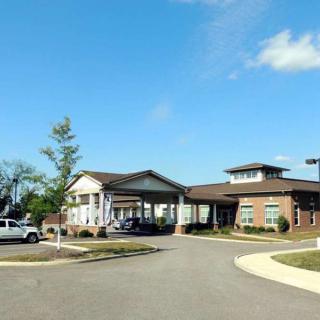 A wide shot of a single-story building with a parking lot and clear blue sky.