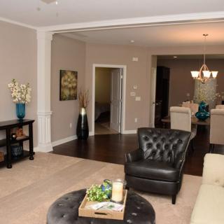 A cozy living room with a leather chair and coffee table, opening into a dining area.