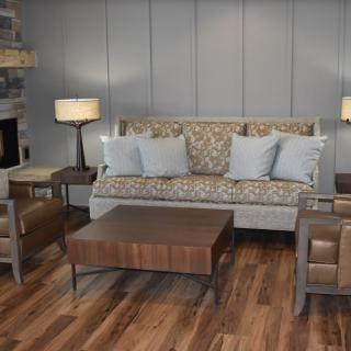 A cozy living room with a patterned sofa, armchairs, and a wooden coffee table on a wooden floor.