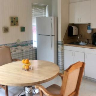 A cozy kitchen and dining area with a round table and chairs, featuring white cabinets and a refrigerator.