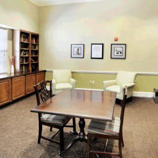A quiet library room with a wooden table, chairs, and bookshelves.