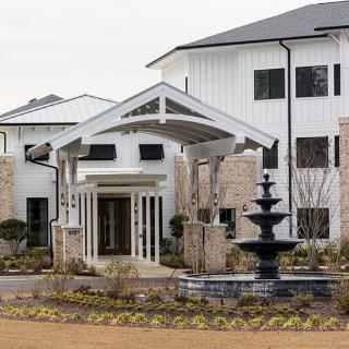 A modern house with a fountain in front and landscaped surroundings.