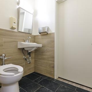 A clean and modern bathroom featuring a toilet, sink, mirror, and simple decor.