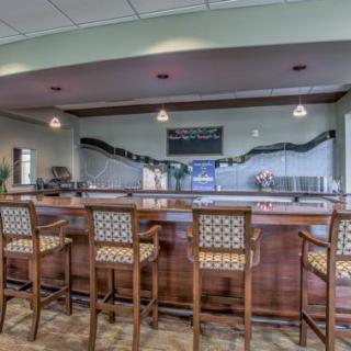 An indoor bar area featuring a wooden counter and high-backed chairs.