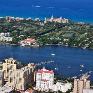 Aerial view of a coastal urban area with buildings and sailboats on the water.