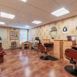 A well-lit hair salon interior featuring styling chairs, mirrors, and a wooden floor.