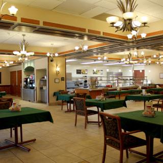 A spacious dining area in a restaurant, featuring tables with green tablecloths and warm lighting.