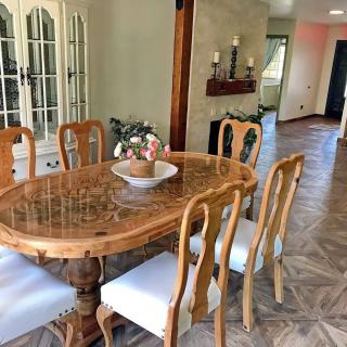 A cozy dining room featuring a wooden table with matching chairs, elegantly decorated with candles and a vase centerpiece.