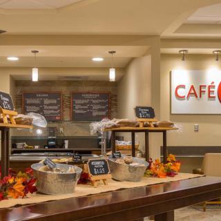 A cozy cafe interior with a variety of food items on display, featuring autumn-themed decorations.