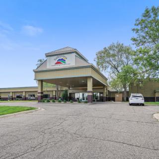 A hotel entrance with a covered driveway and parking area.