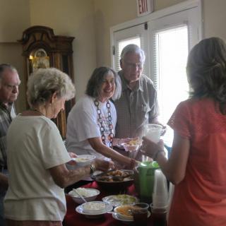 A group of people socializing around a table with food.