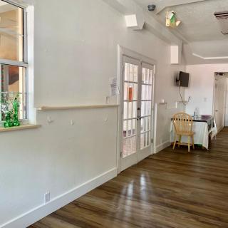 A bright and airy interior with wooden flooring, featuring a dining area next to French doors and decorative plants.